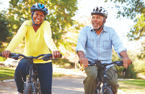 Two older people riding bicycles wearing helmets