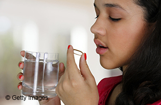 Teenage girl takes pill with glass of water